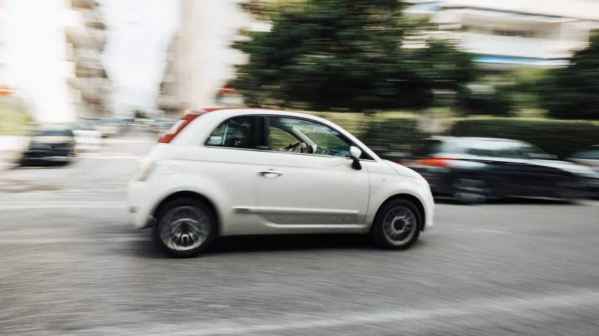 White car speeding through city street with motion blur effect highlighting fast motion.